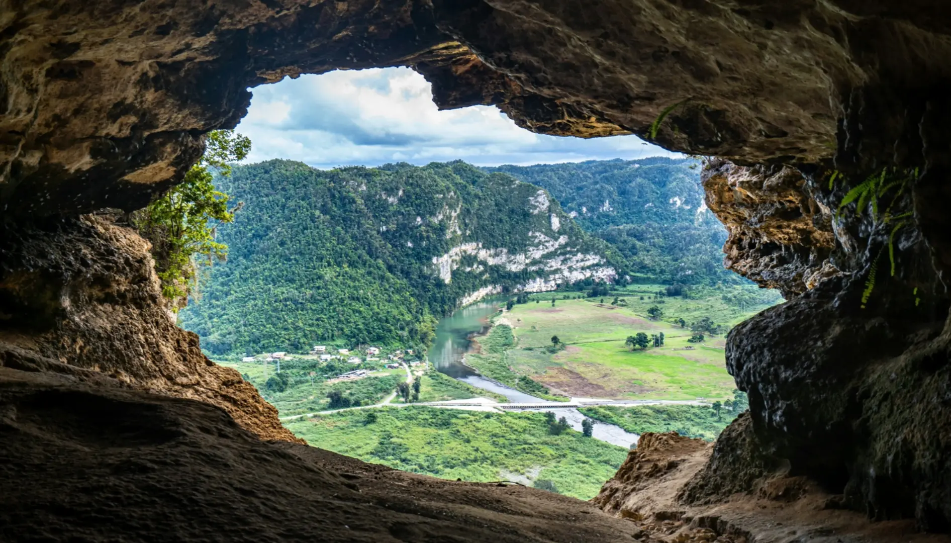 View from inside Cueva Ventana in Puerto Rico, showing the opening of the cave framing mountains covered with trees.