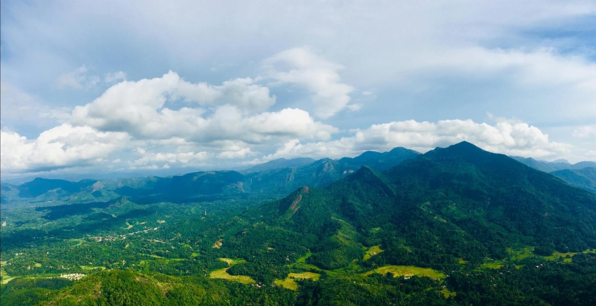 Aerial view of lush mountains in Sri Lanka, covered with dense trees and vibrant vegetation, showcasing the rich natural landscape.